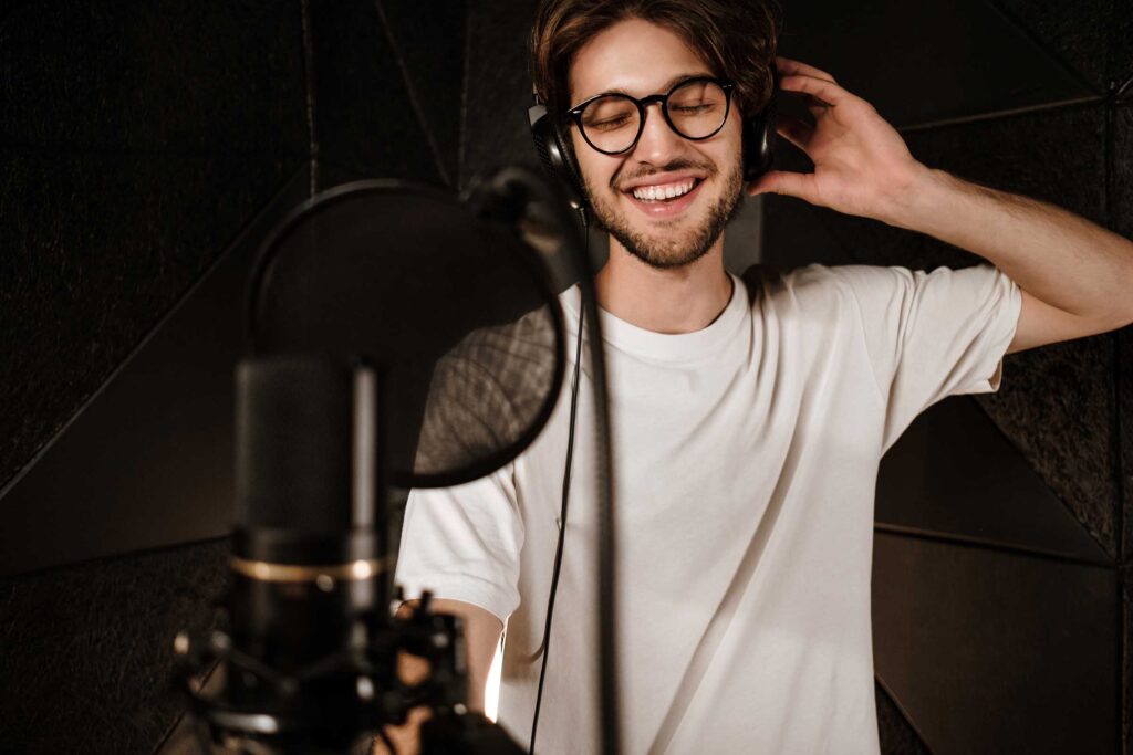 young-attractive-male-singer-in-headphones-joyfull-PGDEZ8B.jpg